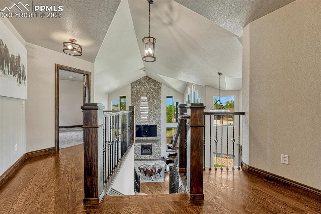 Image 18 of 50: Staircase with wood finished floors, vaulted ceiling, a textured ceiling, b