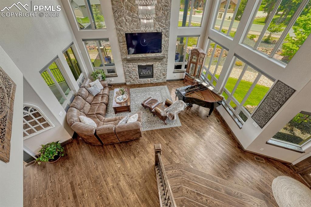 Image 19 of 50: Living room with a towering ceiling, a stone fireplace, and wood finished f