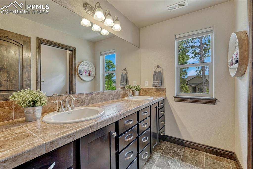 Image 22 of 50: Full bathroom with baseboards and double vanity