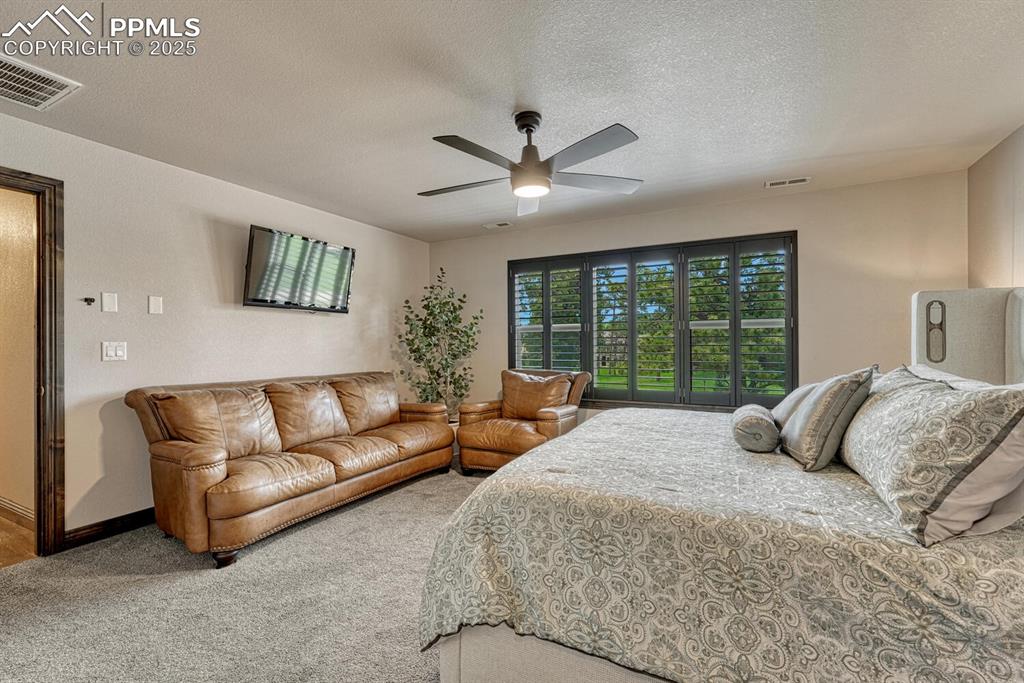 Image 25 of 50: Bedroom with a textured ceiling, carpet flooring, a ceiling fan, and basebo