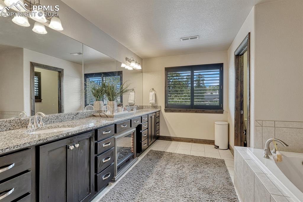 Image 28 of 50: Full bath with double vanity, a garden tub, tile patterned flooring, and a 