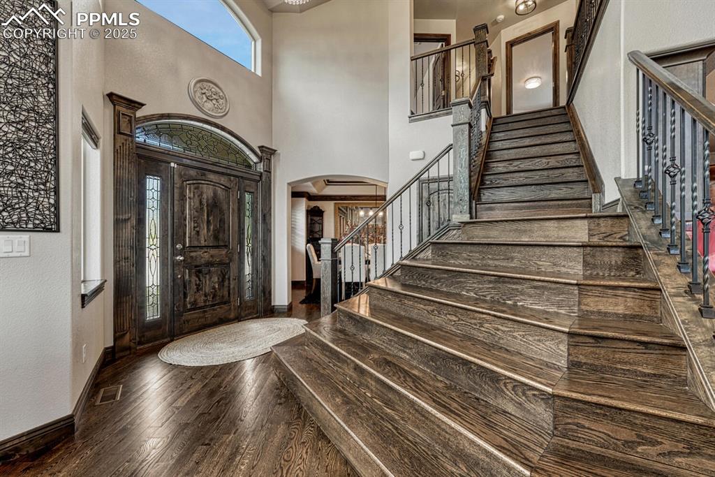 Image 3 of 50: Entrance foyer featuring arched walkways, baseboards, hardwood / wood-style