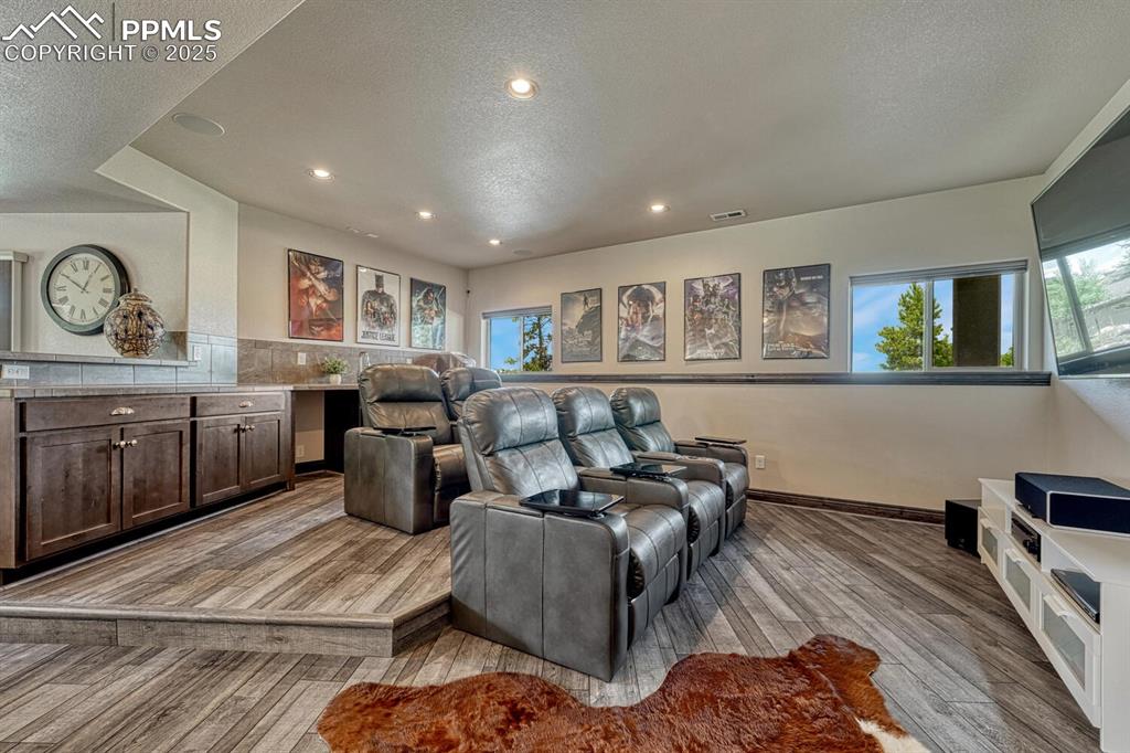 Image 31 of 50: Home theater room with light wood-style floors, healthy amount of natural l