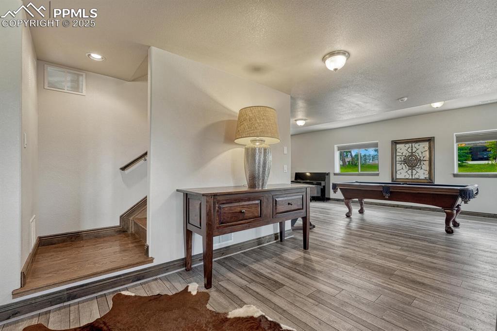 Image 33 of 50: Game room featuring wood finished floors, a textured ceiling, baseboards, a