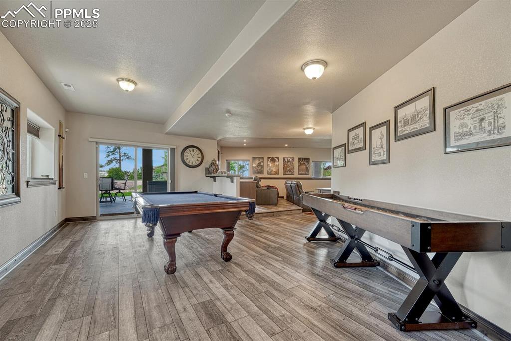 Image 35 of 50: Rec room with pool table, wood finished floors, a textured ceiling, and bas