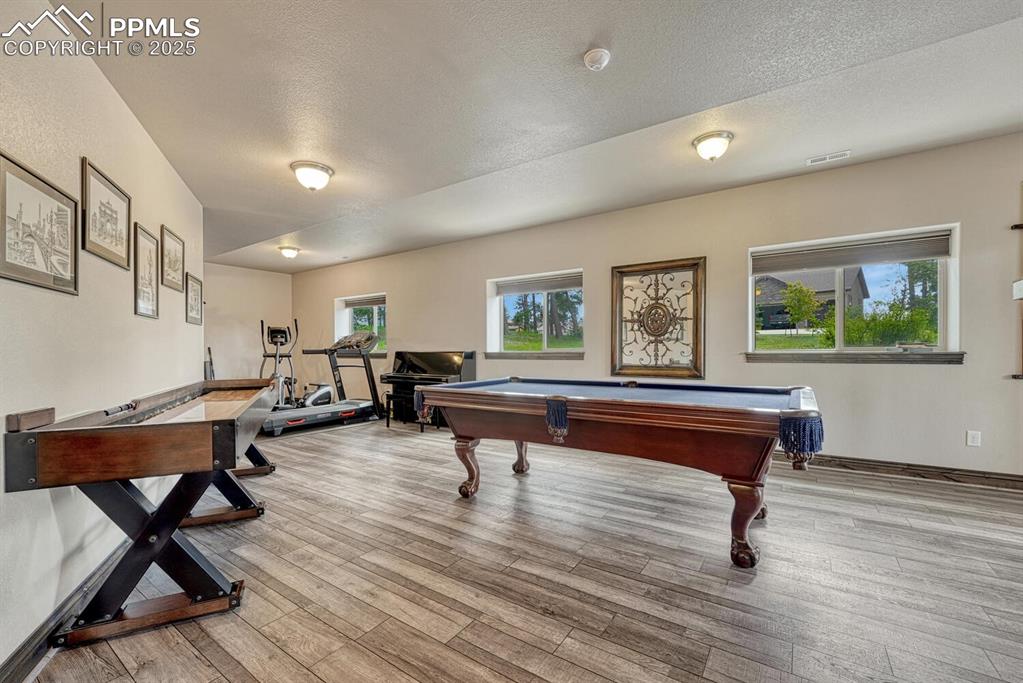 Image 36 of 50: Game room featuring pool table, wood finished floors, a textured ceiling, a
