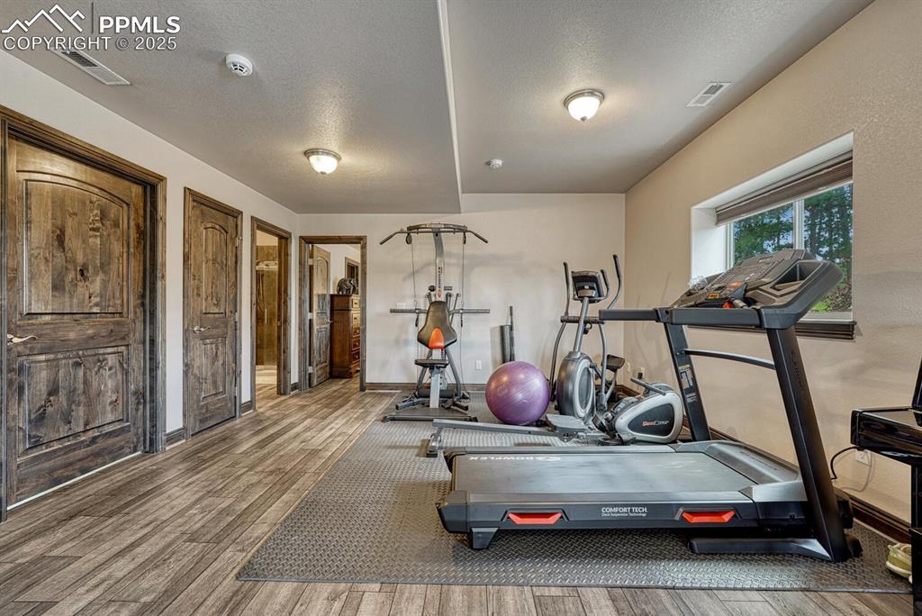 Image 37 of 50: Workout room with wood finished floors, a textured ceiling, and baseboards