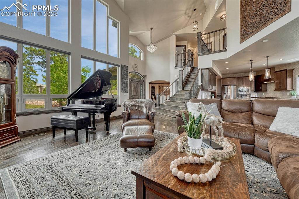 Image 6 of 50: Living room with a high ceiling, wood finished floors, stairway, baseboards