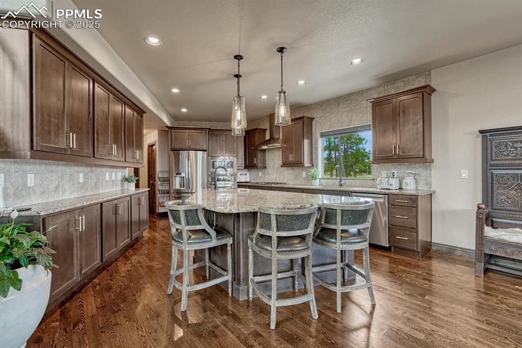 Image 8 of 50: Kitchen featuring stainless steel appliances, backsplash, a kitchen bar, a 