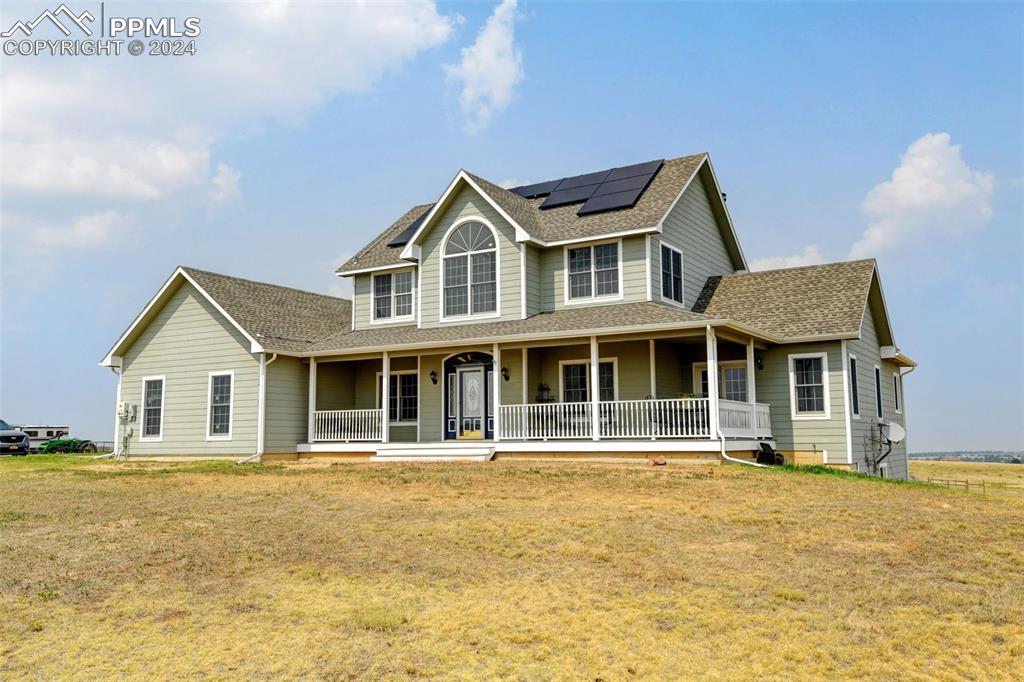 Caption: Farmhouse-style home featuring covered porch and a front lawn