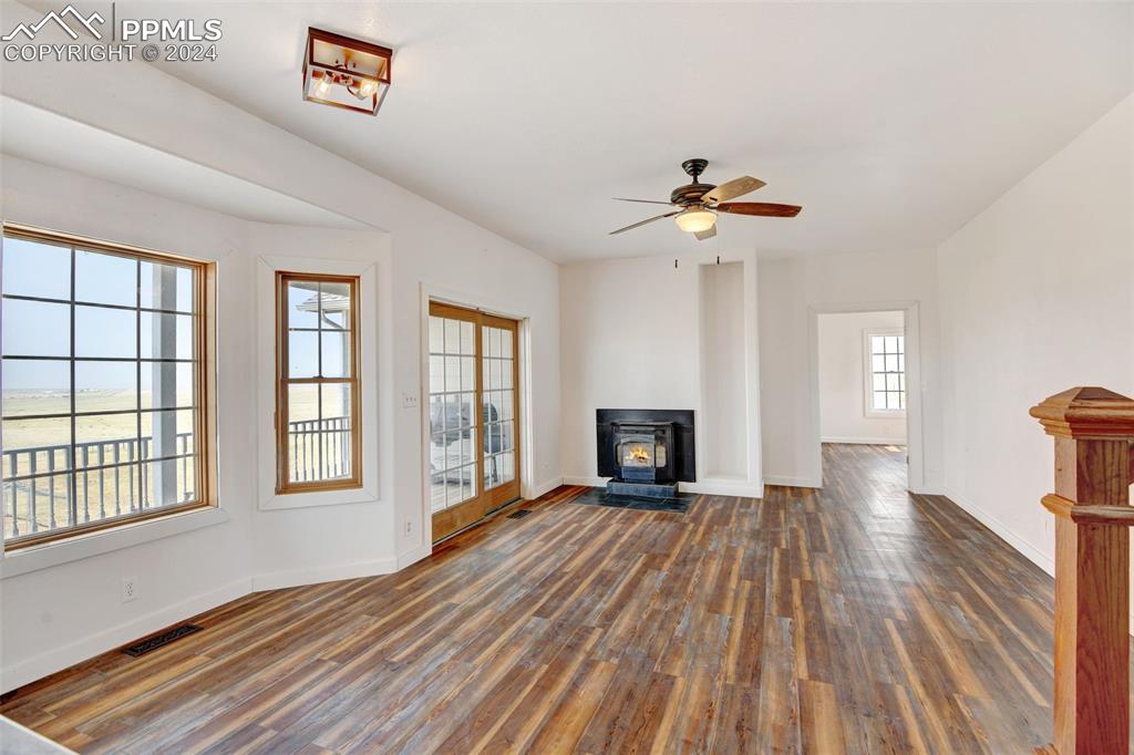 Image 10 of 45: Unfurnished living room with a wood stove, ceiling fan, and dark hardwood /