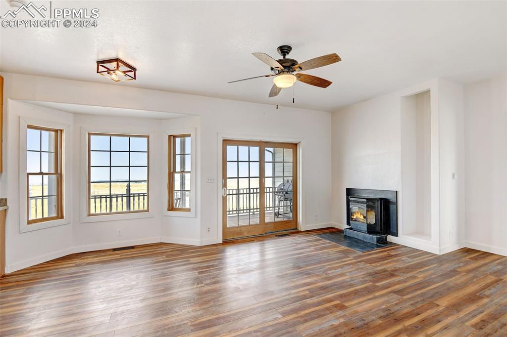 Image 11 of 45: Unfurnished living room featuring a wood stove, plenty of natural light, ce