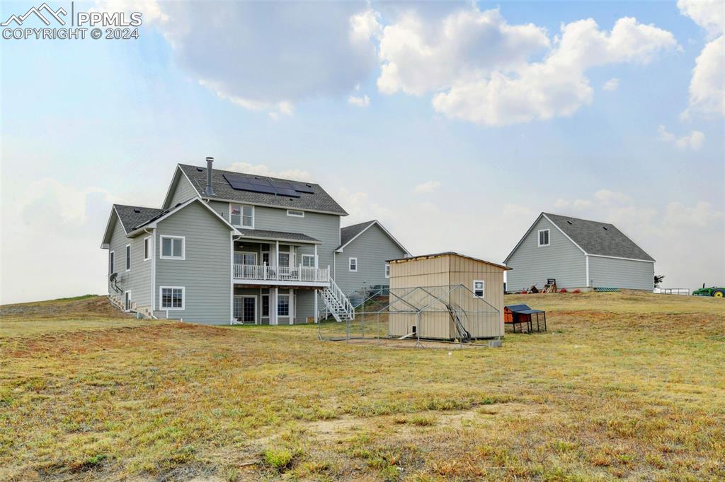 Image 36 of 45: Back of property with solar panels, a yard, and a shed