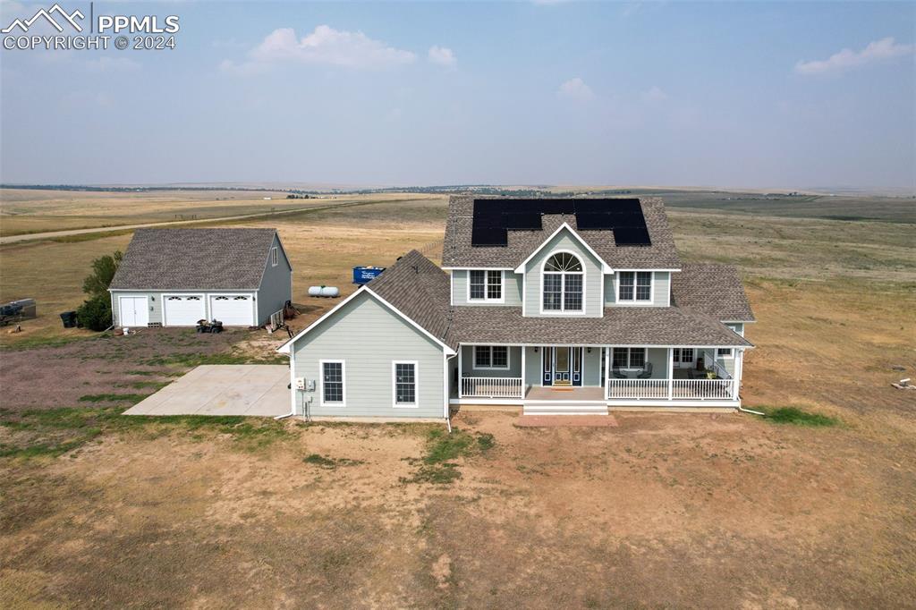 Image 42 of 45: View of front of property with a garage, a porch, an outdoor structure, and