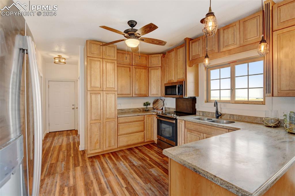 Image 6 of 45: Kitchen featuring hanging light fixtures, appliances with stainless steel f