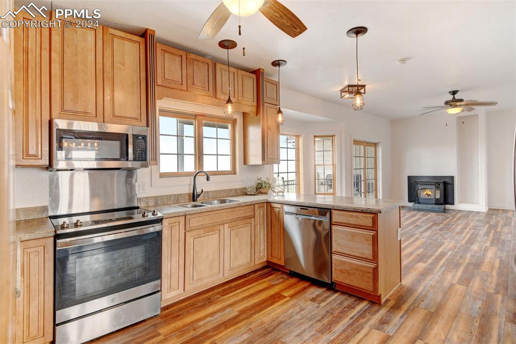 Image 7 of 45: Kitchen with light wood-type flooring, kitchen peninsula, stainless steel a