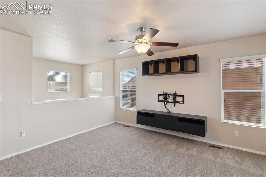 Image 17 of 30: Unfurnished living room featuring a ceiling fan and carpet flooring