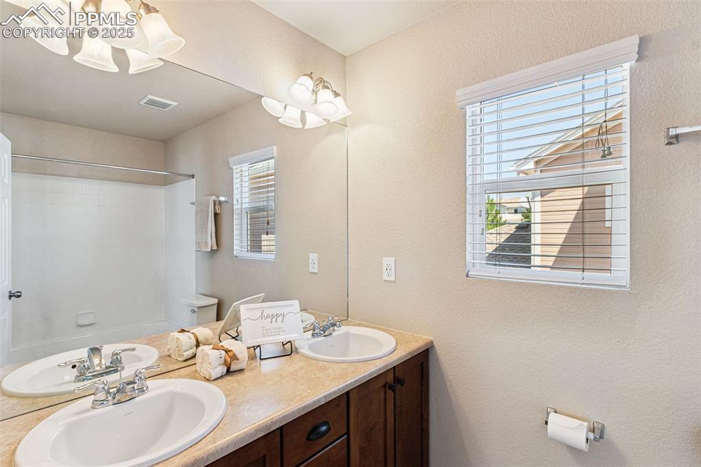 Image 21 of 30: Full bathroom featuring double vanity, plenty of natural light, washtub / s
