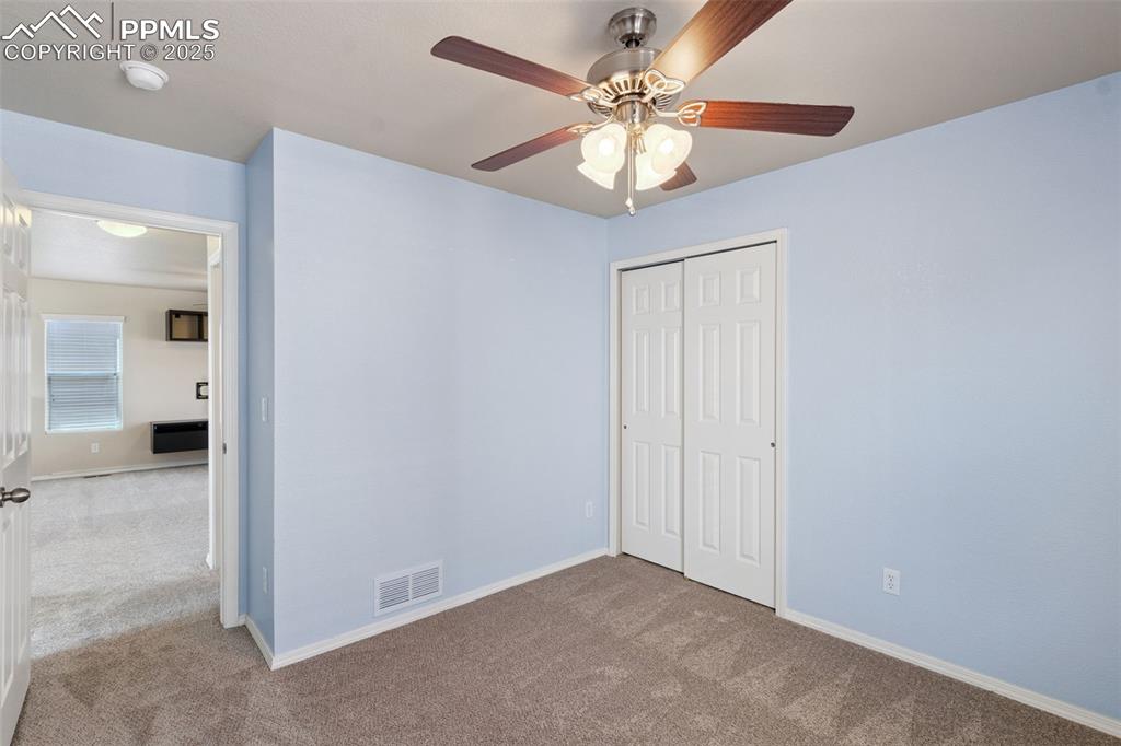 Image 25 of 30: Unfurnished bedroom with carpet floors, a closet, and a ceiling fan