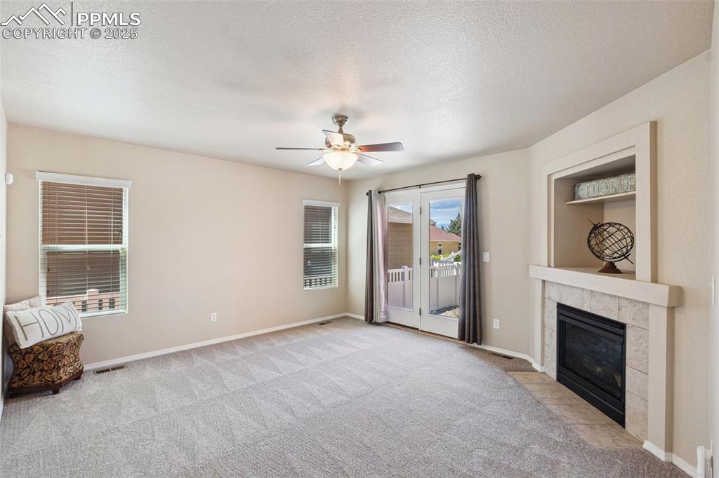 Image 4 of 30: Unfurnished living room with light colored carpet, a ceiling fan, a tile fi