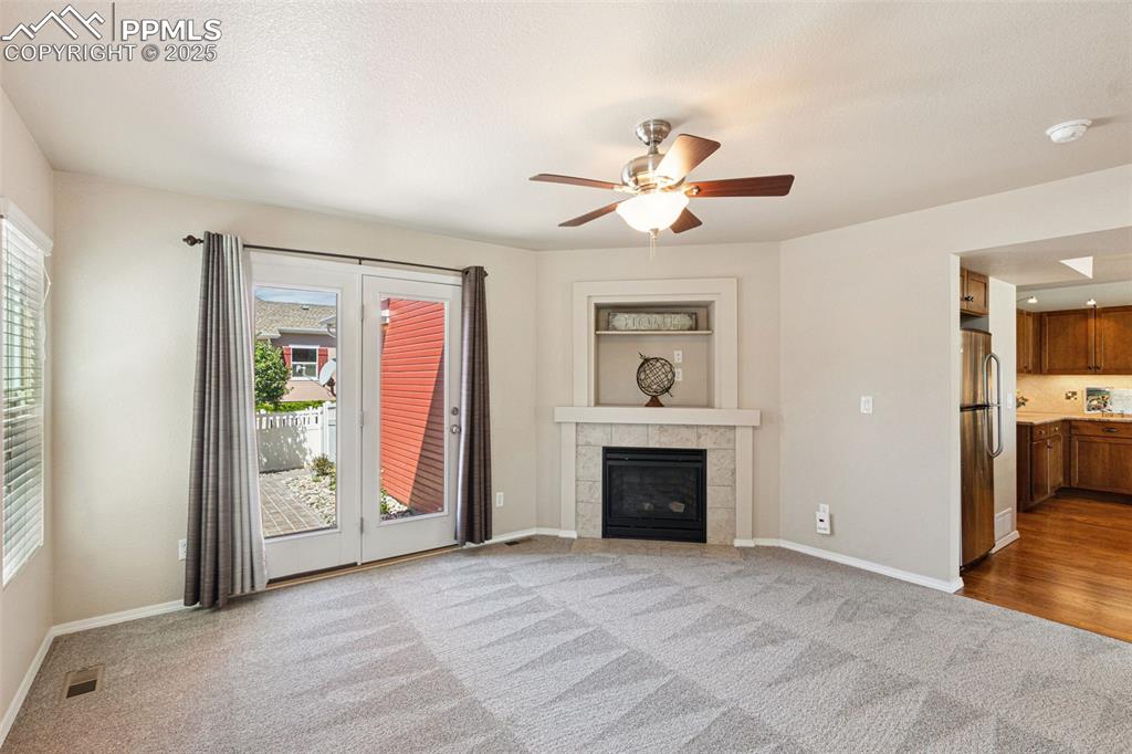 Image 5 of 30: Unfurnished living room featuring carpet, a tile fireplace, and ceiling fan