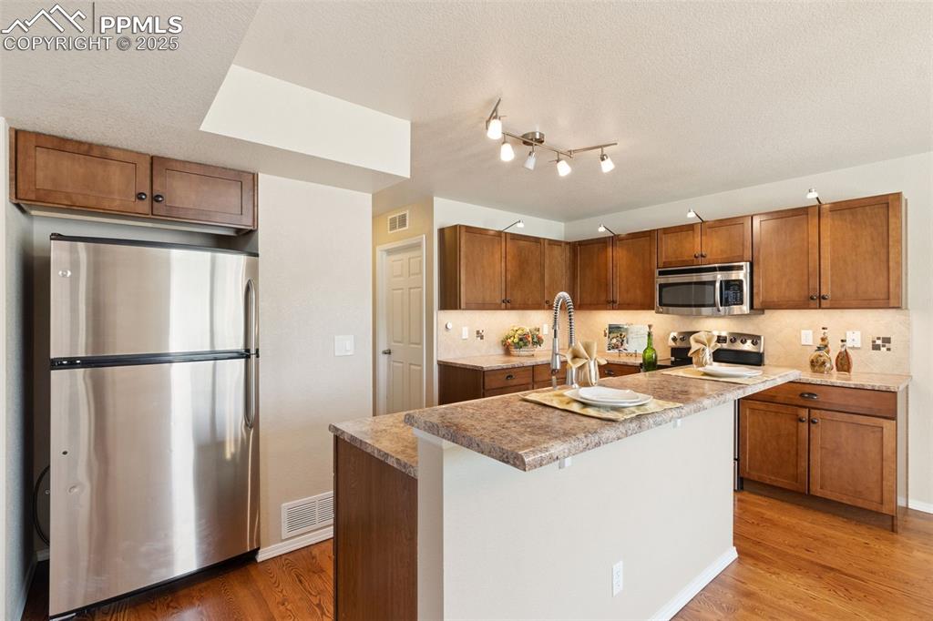 Image 8 of 30: Kitchen featuring stainless steel appliances, tasteful backsplash, light wo