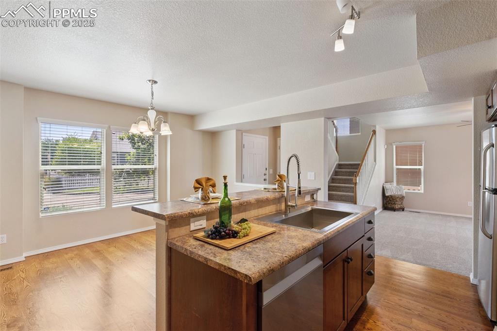Image 9 of 30: Kitchen with light wood finished floors, an island with sink, dishwasher, a