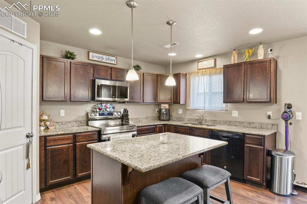 Image 10 of 30: Kitchen featuring stainless steel appliances, a kitchen breakfast bar, dark