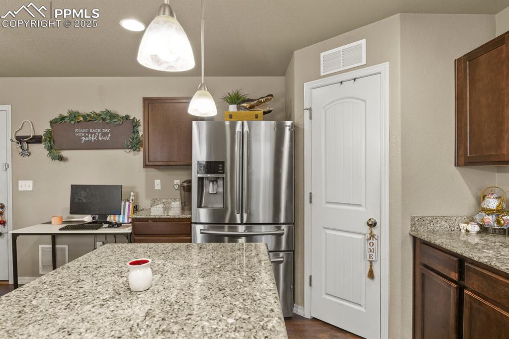 Image 11 of 30: Kitchen with stainless steel fridge with ice dispenser, light stone counter