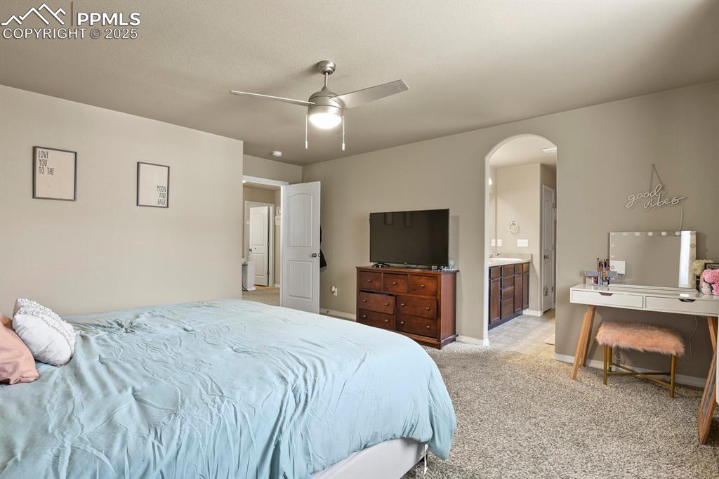 Image 19 of 30: Bedroom featuring arched walkways, light colored carpet, ceiling fan, and c