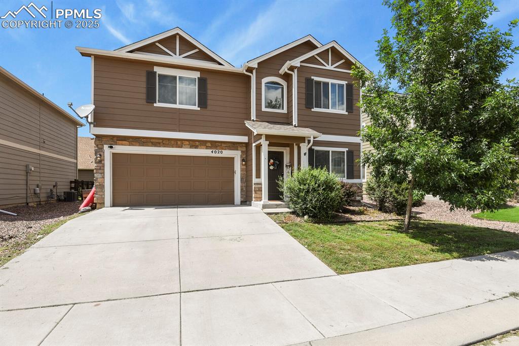 Image 2 of 30: Craftsman-style house with stone siding, an attached garage, concrete drive