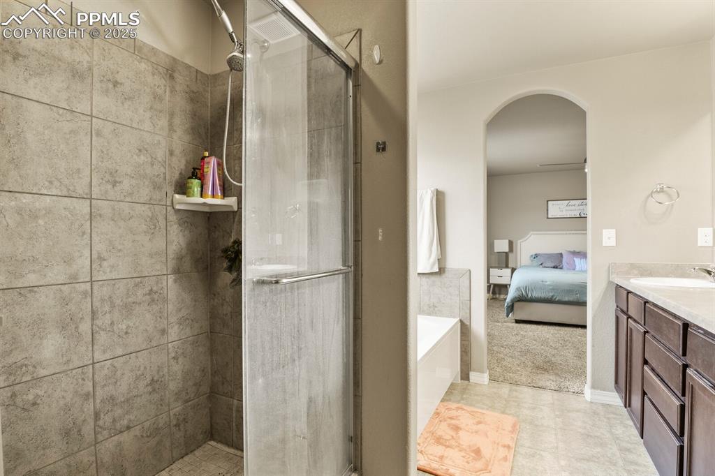 Image 21 of 30: Bathroom with ensuite bath, a stall shower, vanity, a bath, and tile patter