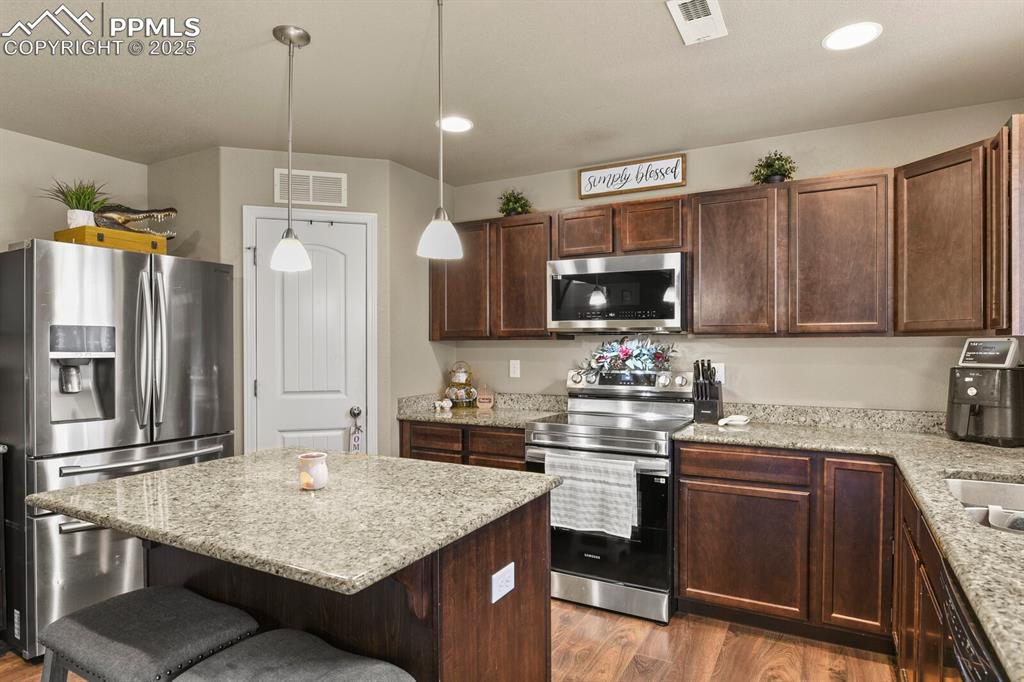 Image 9 of 30: Kitchen featuring stainless steel appliances, a breakfast bar area, wood fi