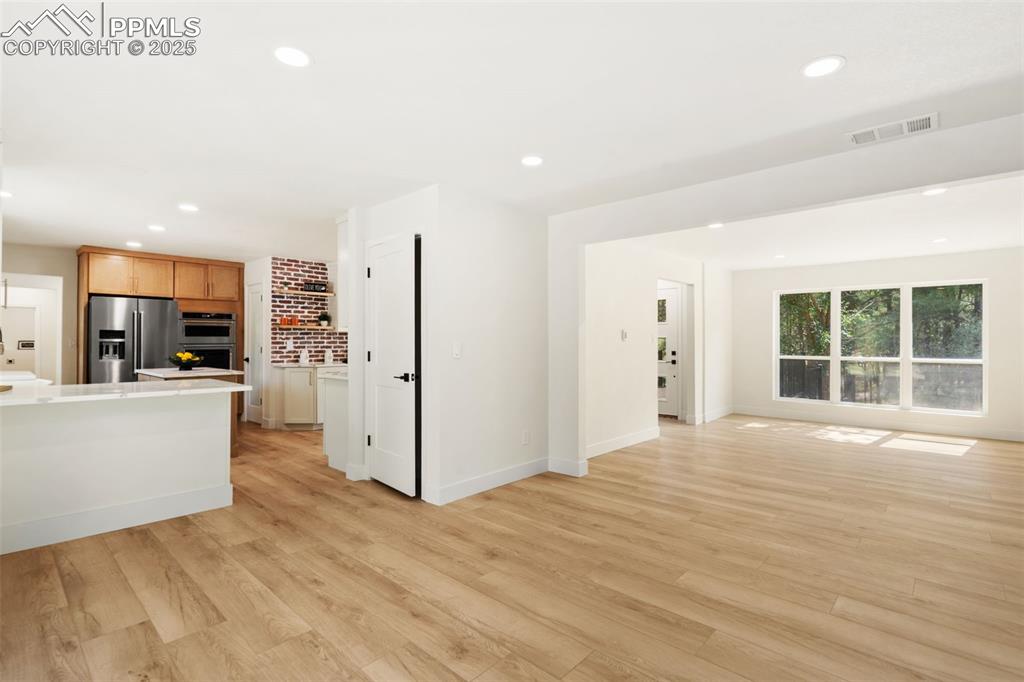 Image 10 of 43: Unfurnished living room with light wood finished floors and recessed lighti