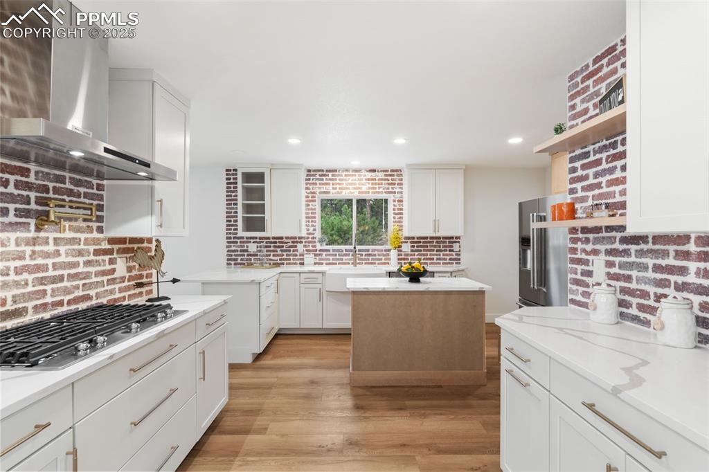 Image 11 of 43: Kitchen featuring wall chimney exhaust hood, white cabinetry, appliances wi