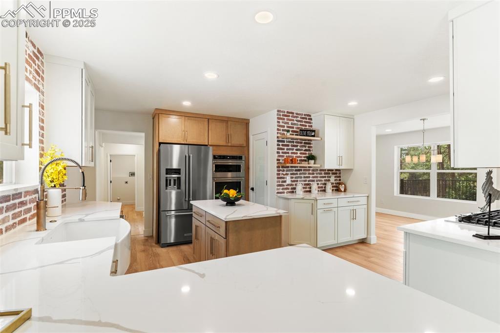 Image 13 of 43: Kitchen featuring light wood-style flooring, light stone countertops, open 