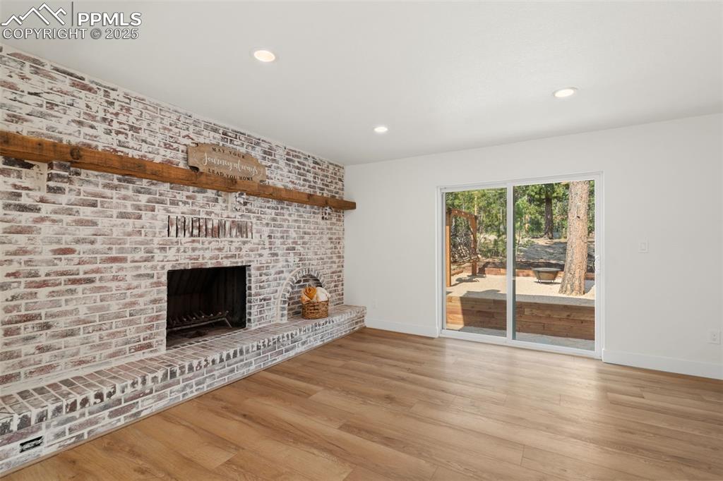 Image 16 of 43: Unfurnished living room featuring a fireplace, wood finished floors, recess