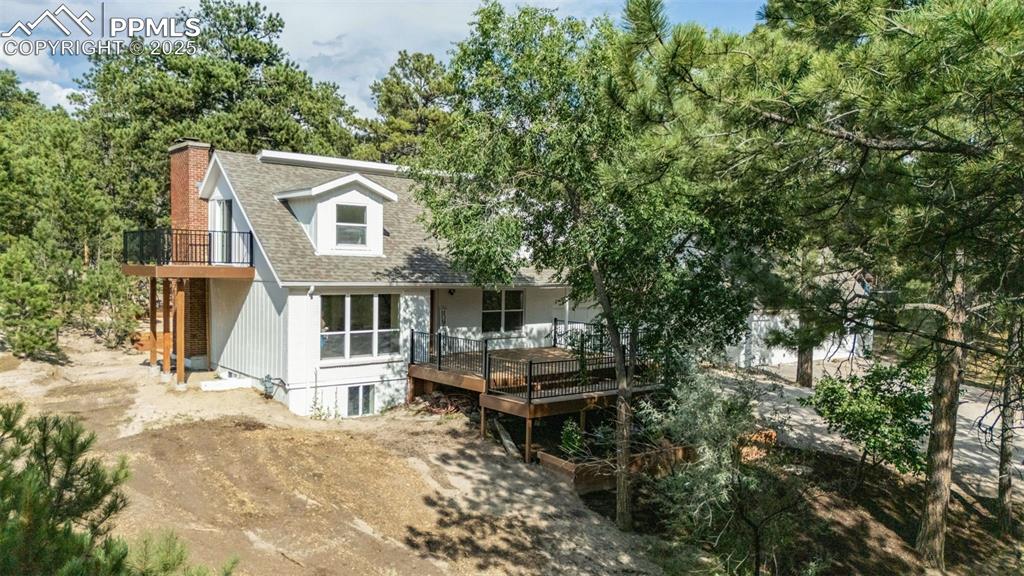 Image 2 of 43: Back of property with a shingled roof, a chimney, a deck, and a balcony