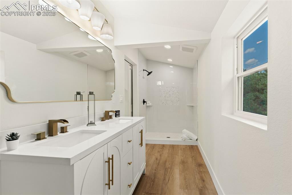 Image 23 of 43: Bathroom with a shower stall, double vanity, light wood-style floors, and l