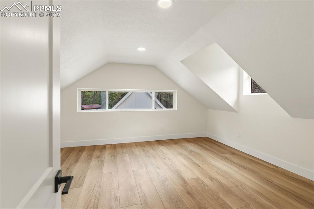 Image 25 of 43: Bedroom with character, featuring vaulted ceiling, light wood finished floo