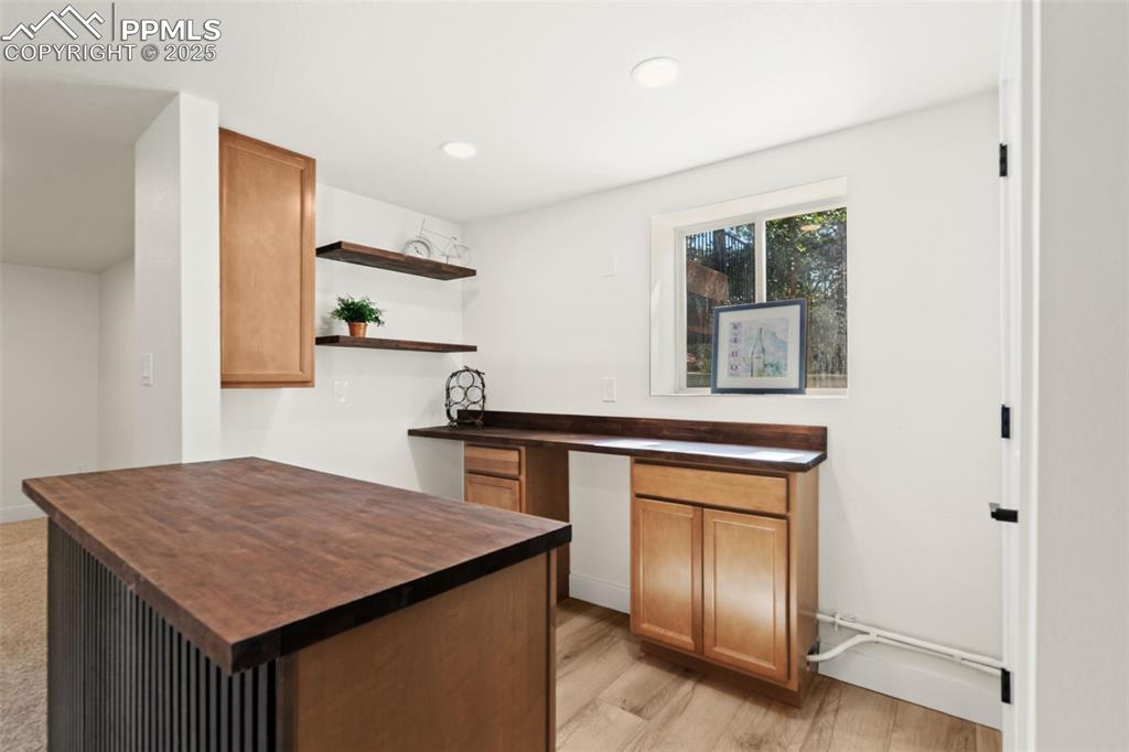 Image 32 of 43: Kitchen featuring butcher block counters, open shelves, brown cabinets, lig