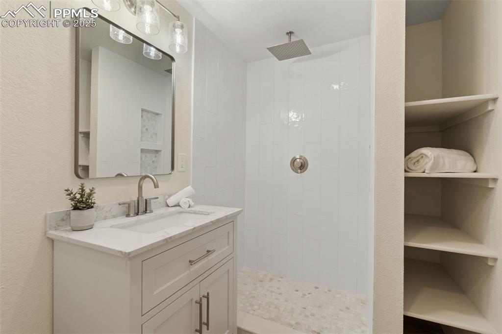 Image 34 of 43: Full bath with vanity, a walk in shower, and a textured wall