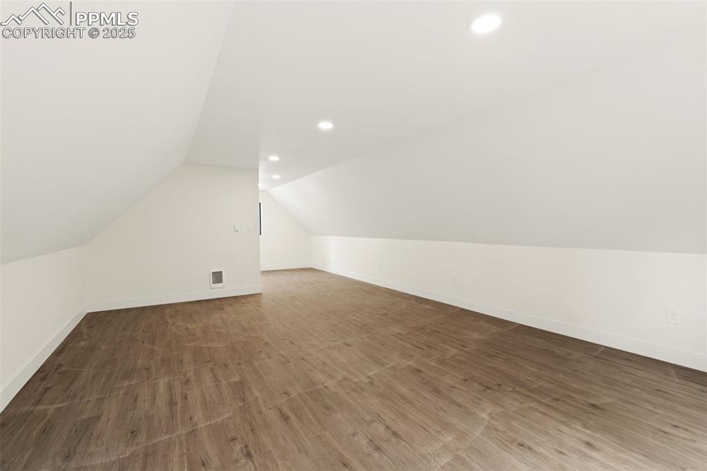 Image 40 of 43: Additional living space featuring dark wood-style flooring, lofted ceiling,