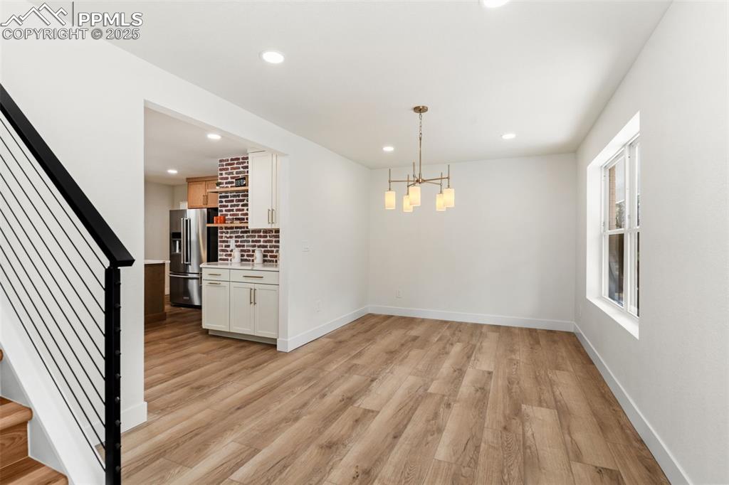 Image 5 of 43: Unfurnished dining area with stairway, a chandelier, light wood-type floori