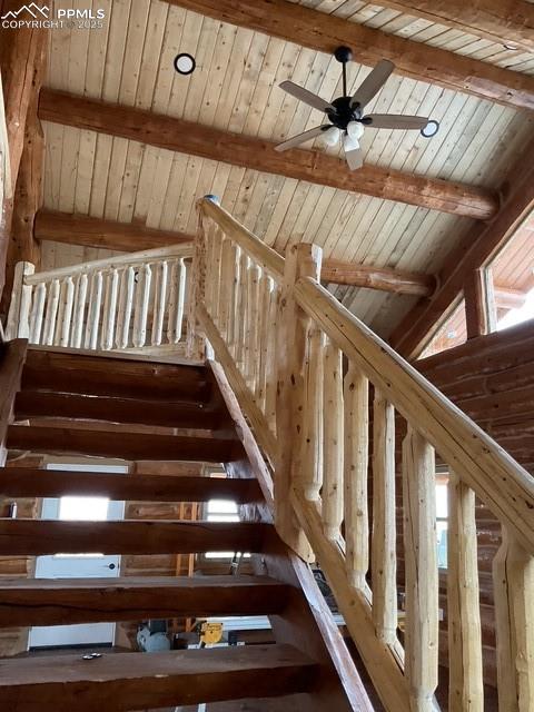 Image 24 of 28: Stairs featuring beam ceiling, wood ceiling, and ceiling fan