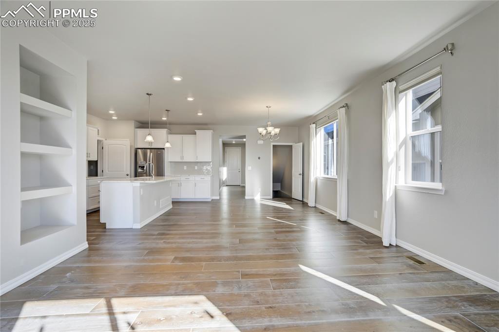 Image 10 of 44: Unfurnished living room featuring a chandelier, light wood-type flooring, r