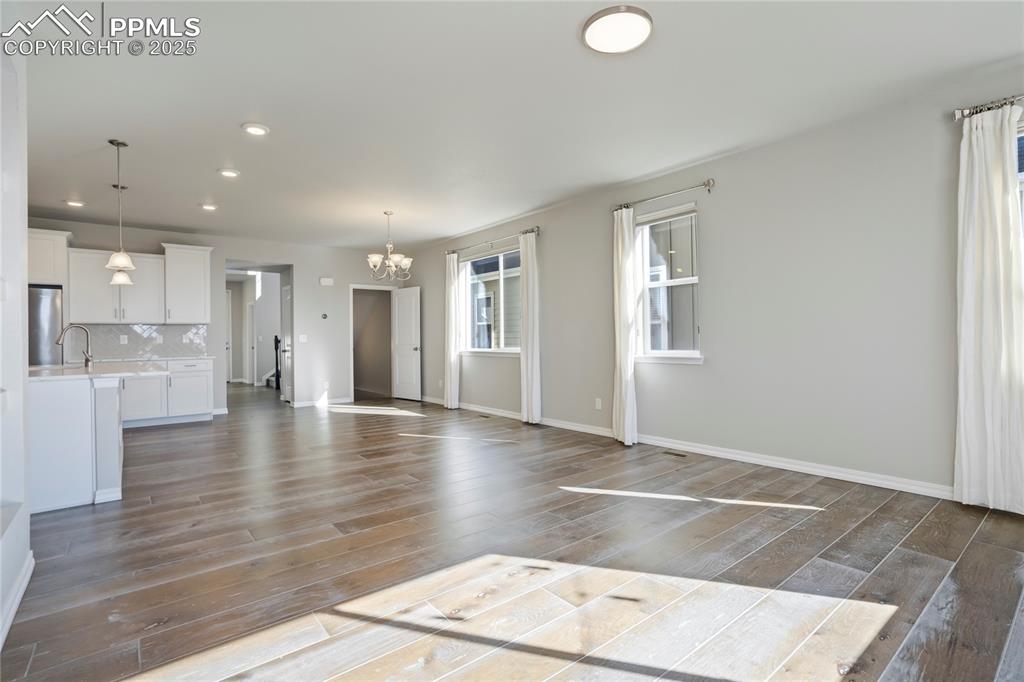 Image 11 of 44: Unfurnished living room featuring a chandelier, dark wood-style floors, rec