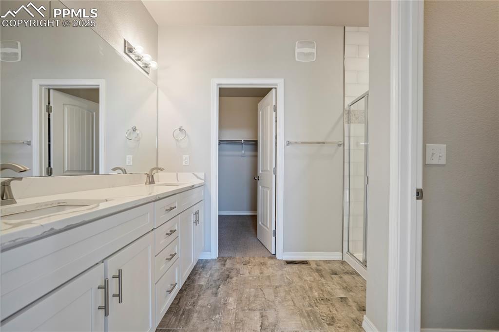 Image 16 of 44: Bathroom with a stall shower, double vanity, light wood-style floors, and a