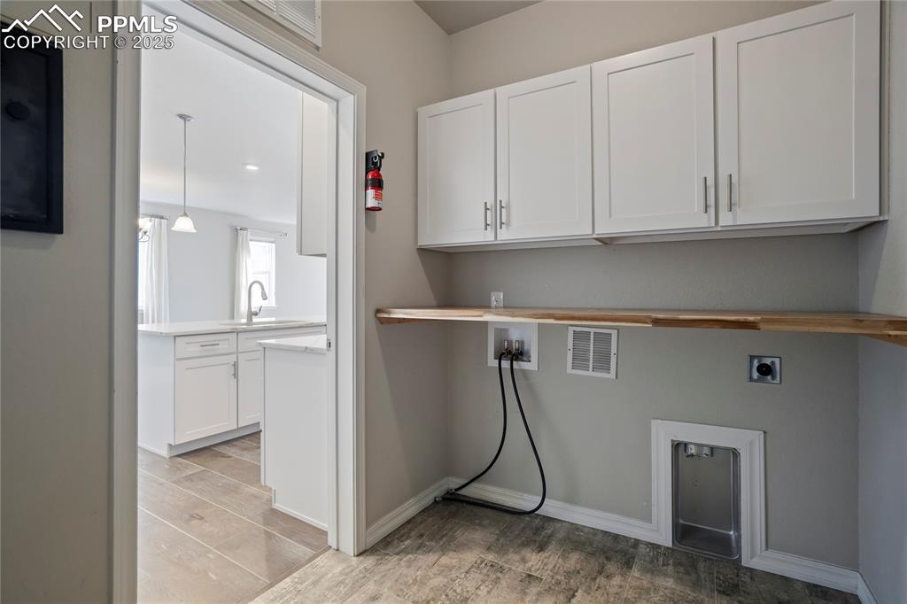 Image 18 of 44: Washroom featuring washer hookup, light wood-style floors, cabinet space, a