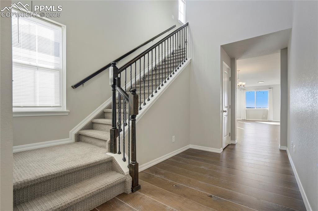 Image 2 of 44: Stairs featuring wood-type flooring, a chandelier, and a high ceiling